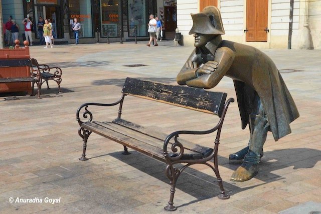 Sculpture of a man leaning on a bench in the city street