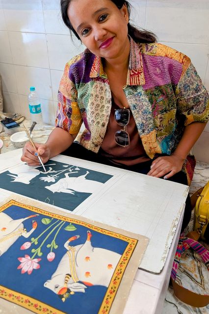 Divya Ramachandran painting a Pichwai style cow - a Kamadhenu, the wish-fulfilling 